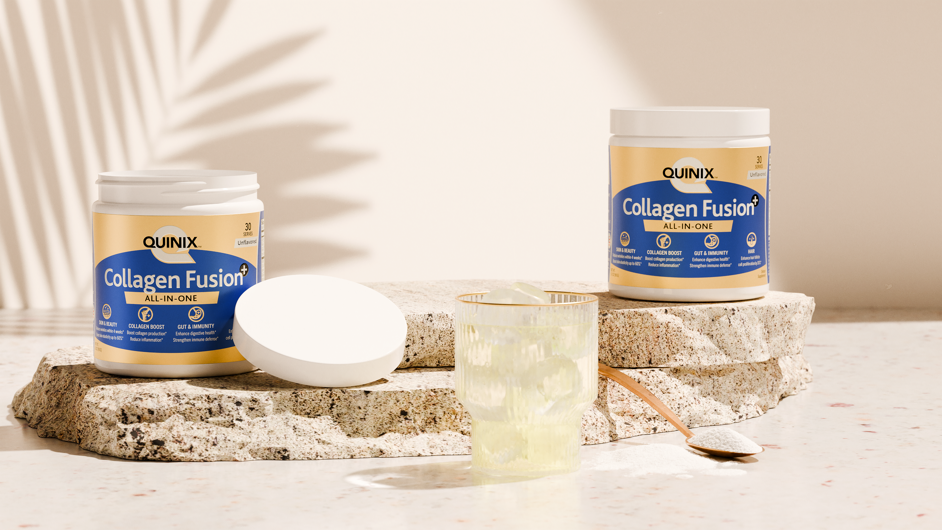 Two jars of QUINIX Collagen Fusion+ all-in-one supplement displayed on textured stone with glass of ice water and wooden scoop, in warm daylight—hero image representing beauty, wellness, and simplicity.